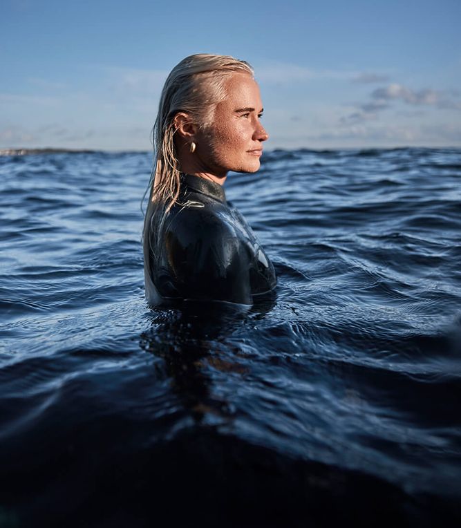 A woman in a wetsuit in the ocean.